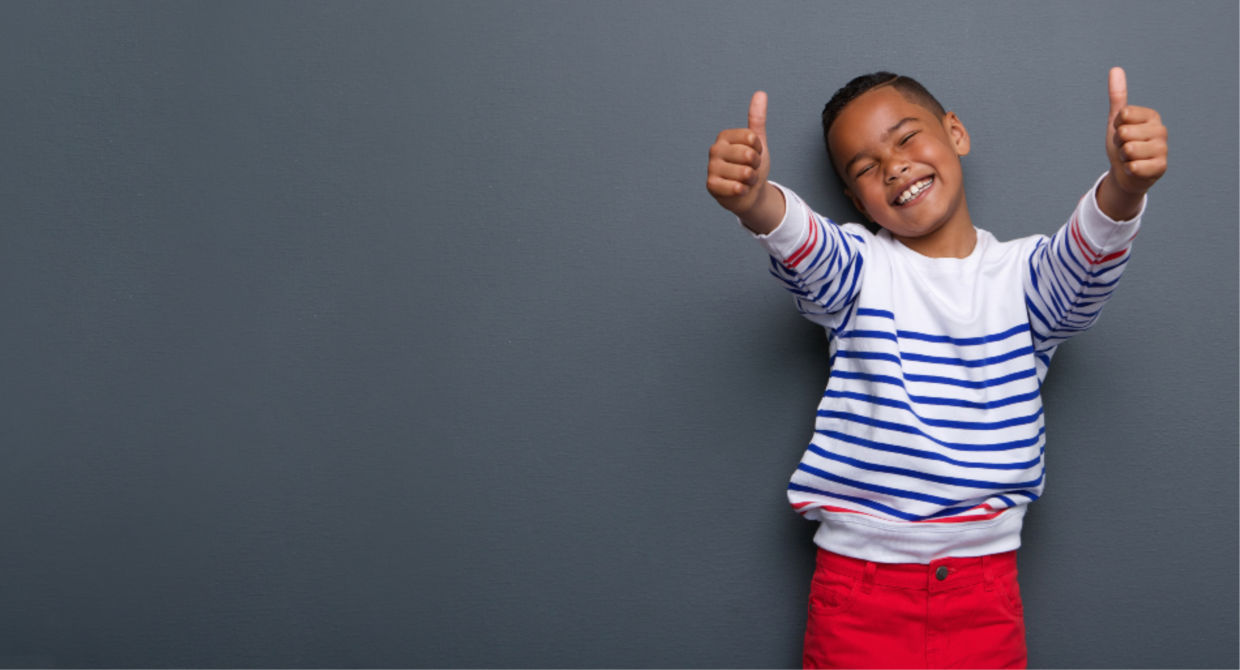 Little black boy giving two thumbs up and smiling
