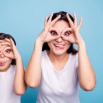 A mom and a daughter making glasses with their hands over their eyes