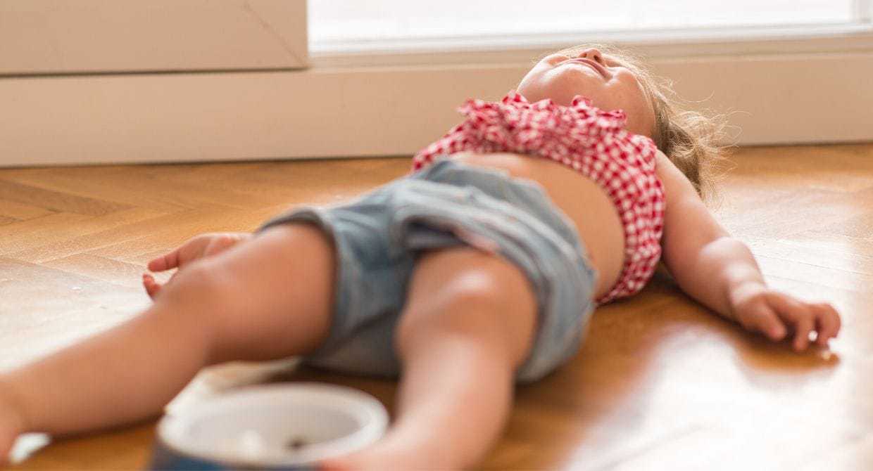 Young girl lying on ground having a tantrum