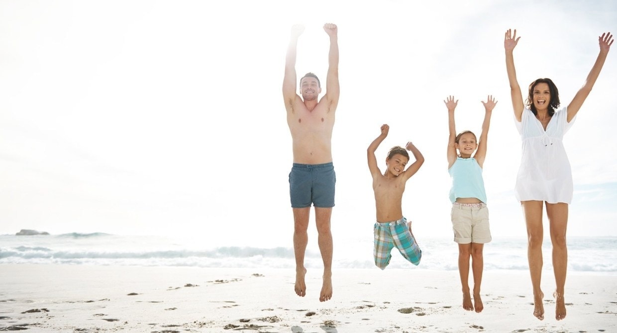 family jumping for joy on the beach