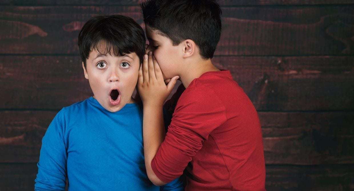 Boy telling another boy a secret