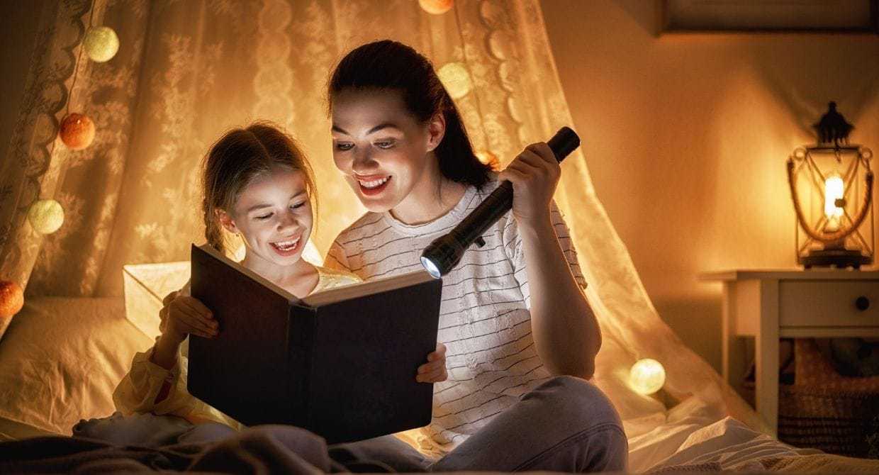 mom and daughter reading story with flashlight