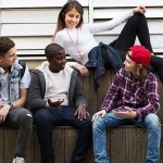 group of teens talking with skateboards and phones