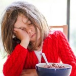 young girl tired sleeping at breakfast table