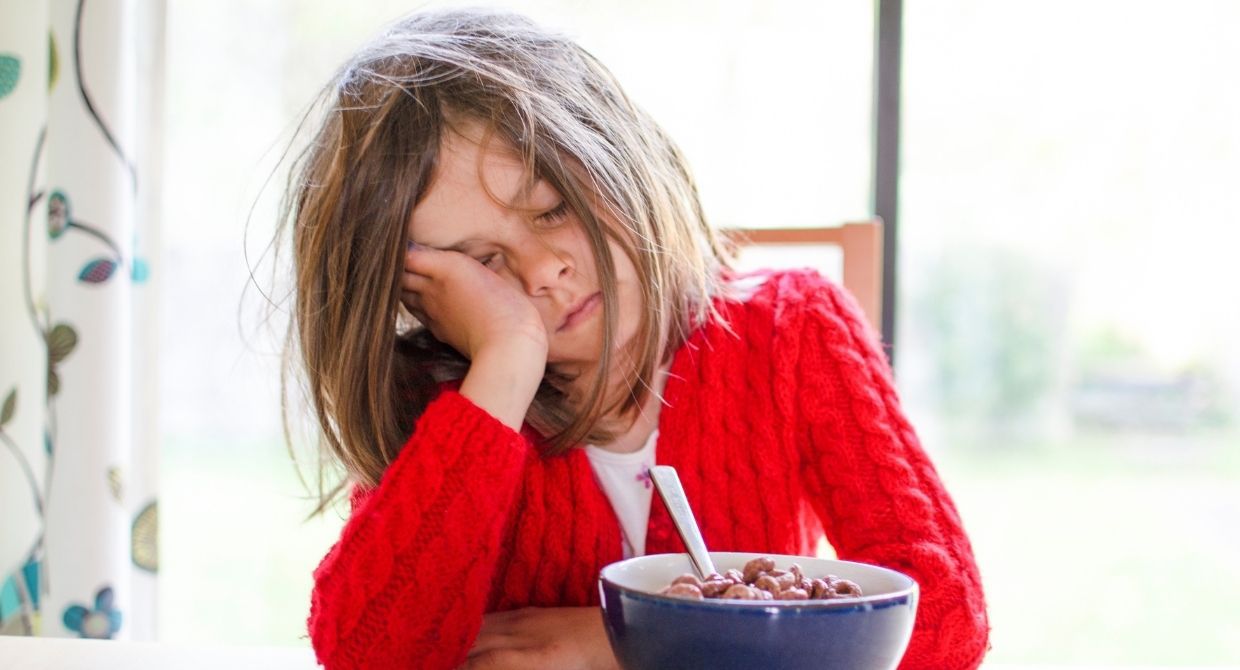 young girl tired sleeping at breakfast table