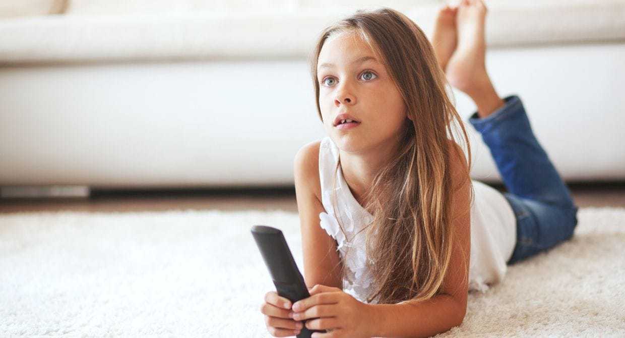 8 year old girl lying down on carpet watching tv
