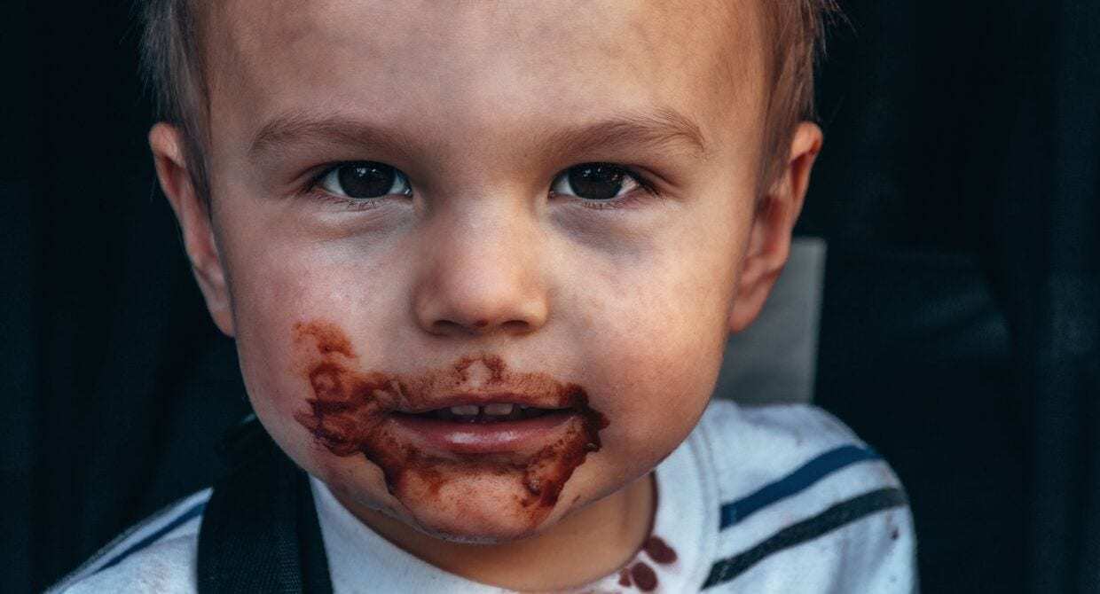 Young boy with chocolate all over his mouth looking at the camera