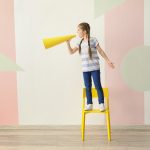 Girl standing on chair yelling through a megaphone