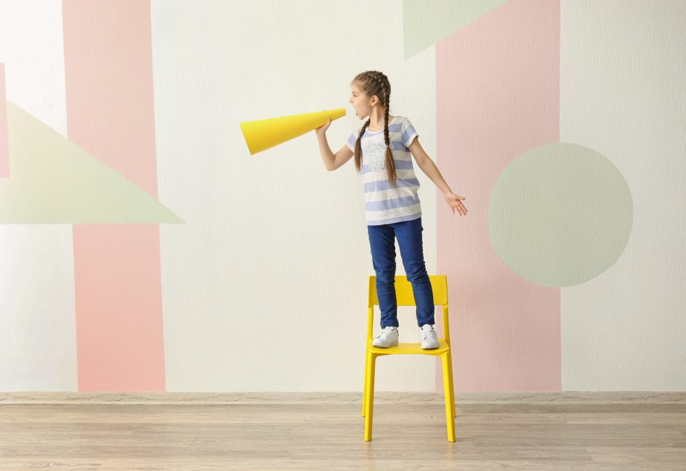 Girl standing on chair yelling through a megaphone