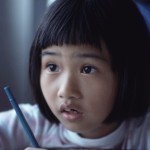 Young girl holding a pencil at her desk
